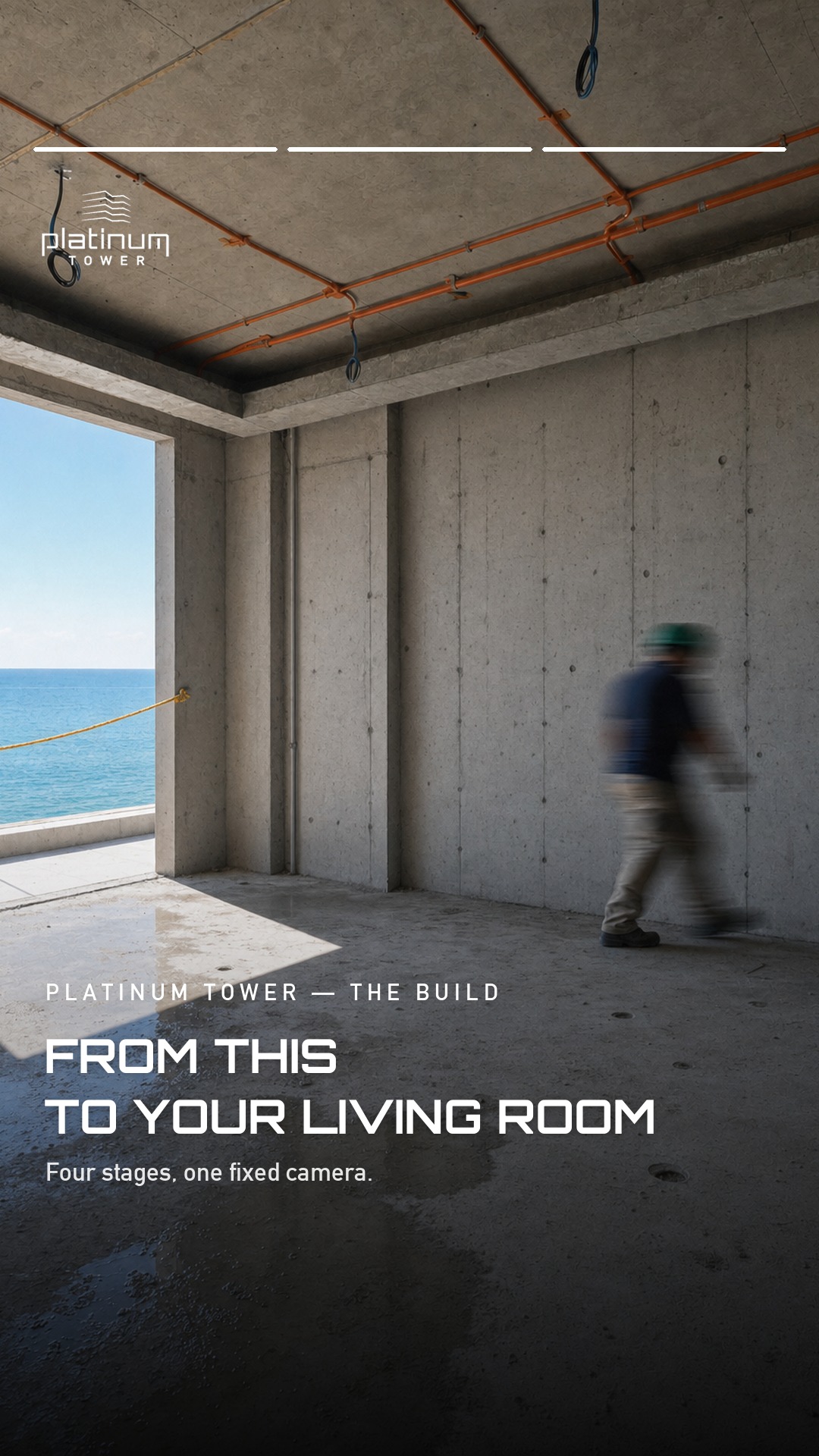 A bare concrete shell at Platinum Tower with exposed orange electrical conduit on the ceiling, an open bay facing the Atlantic, and a hard hatted worker walking through the unfinished room
